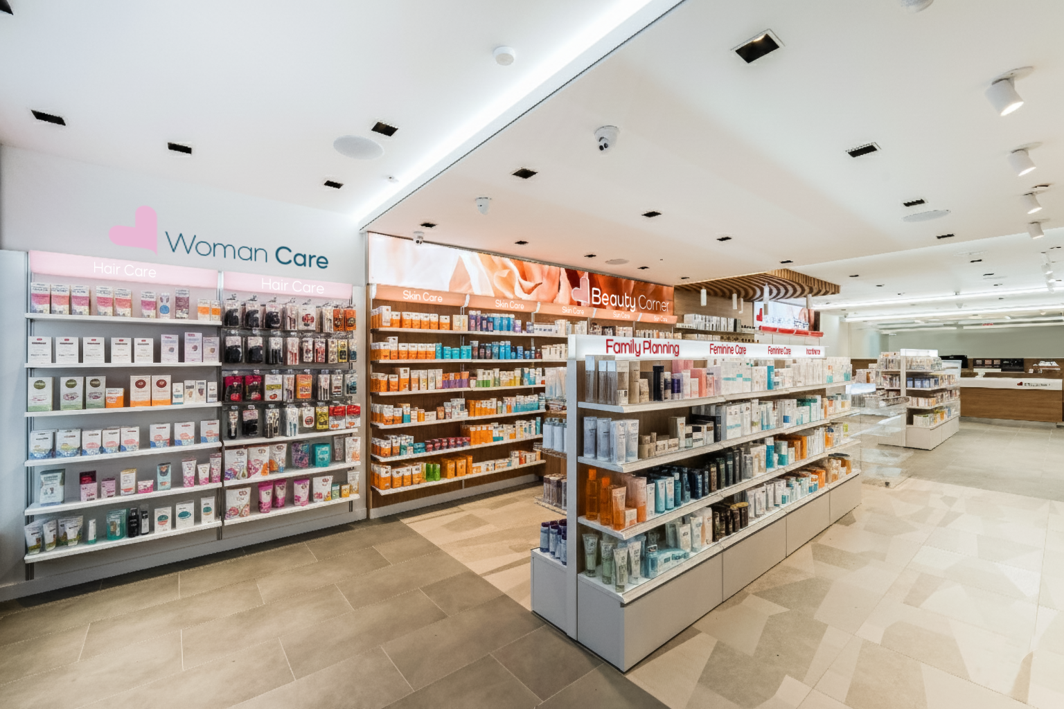 Central pharmacy aisle with fully stocked shelving and clear product category signage.